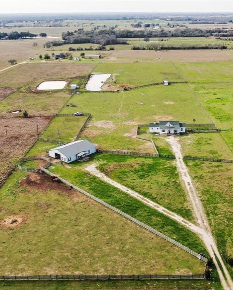 Aerial view of the farm with the house, barn, ponds, and fenced pastures