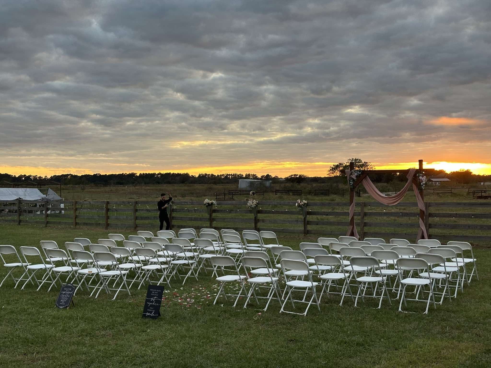 Chairs set up on the pasture for a gathering under a sunset sky