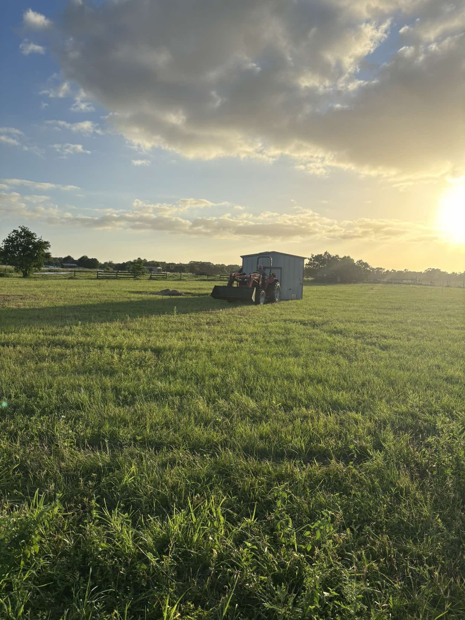 The tractor parked out in the green pasture at golden hour