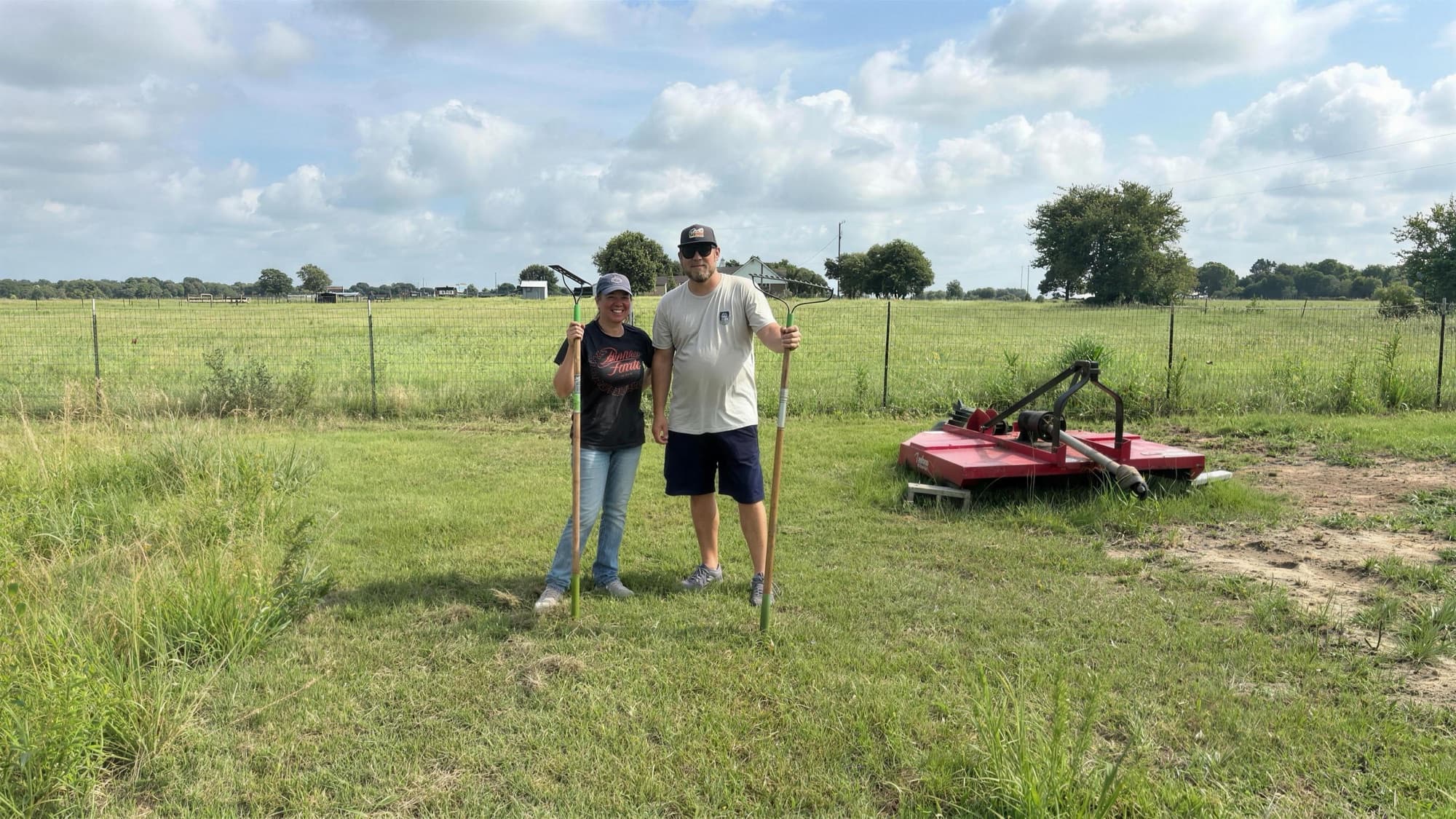 Two people carrying garden tools across the farm on a workday