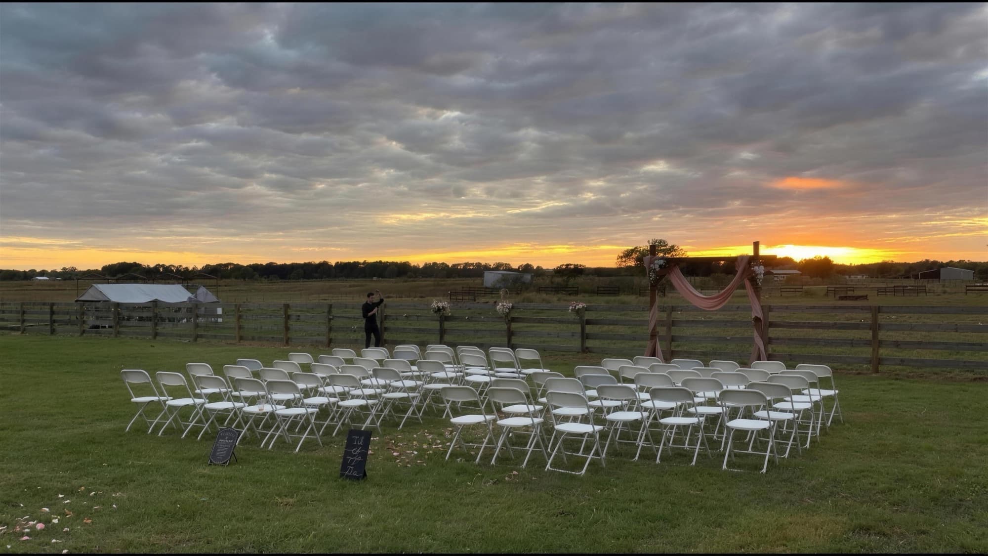 An outdoor ceremony set up in a farm field at sunset
