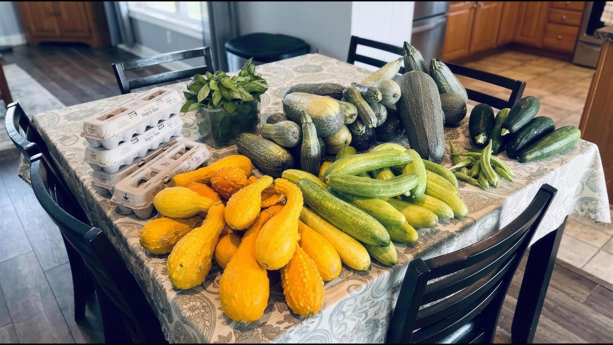 A table spread with a summer harvest of squash, cucumbers, and fresh eggs from the farm