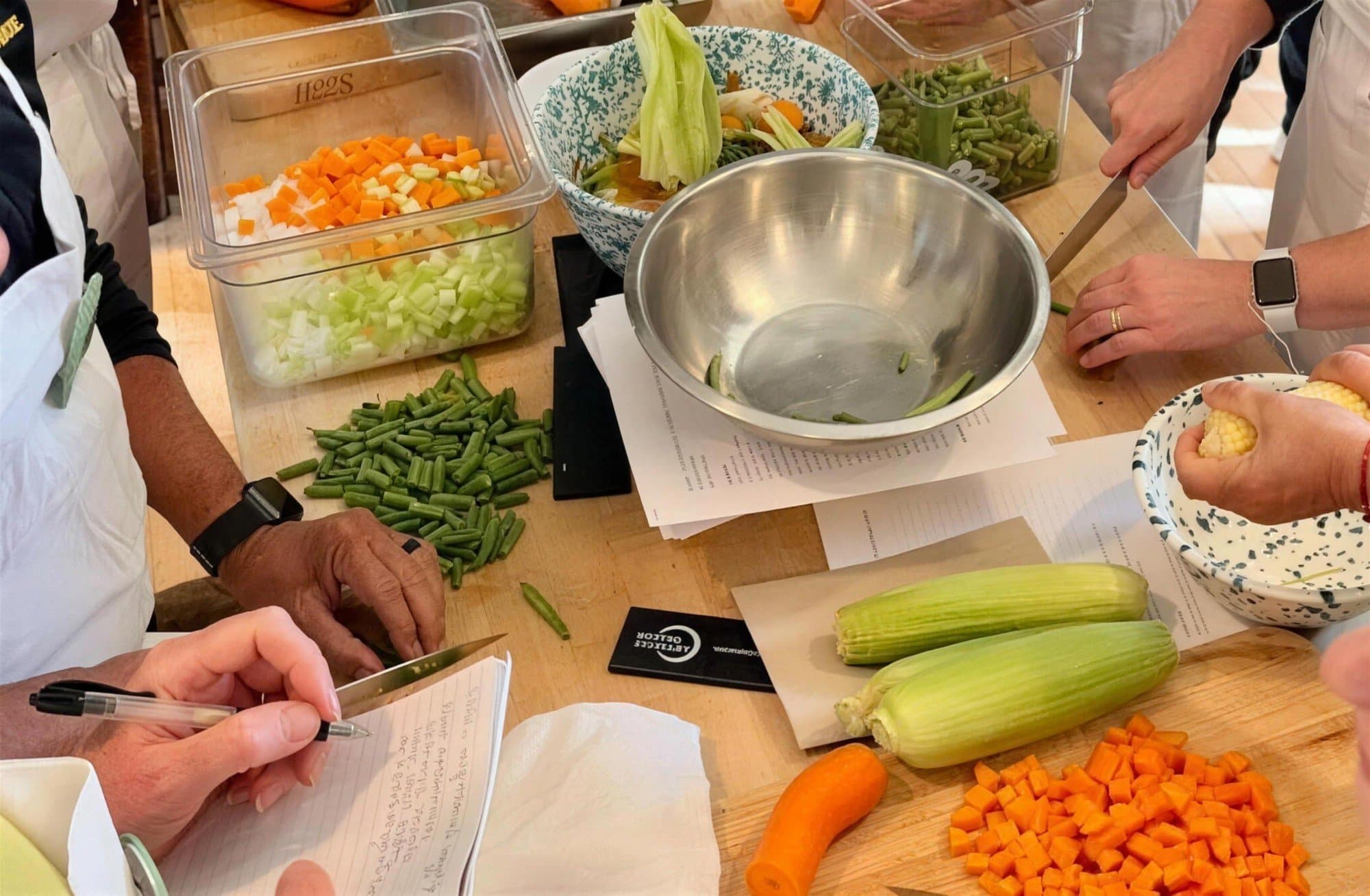 Guests chopping fresh vegetables together at a farm-to-table cooking class