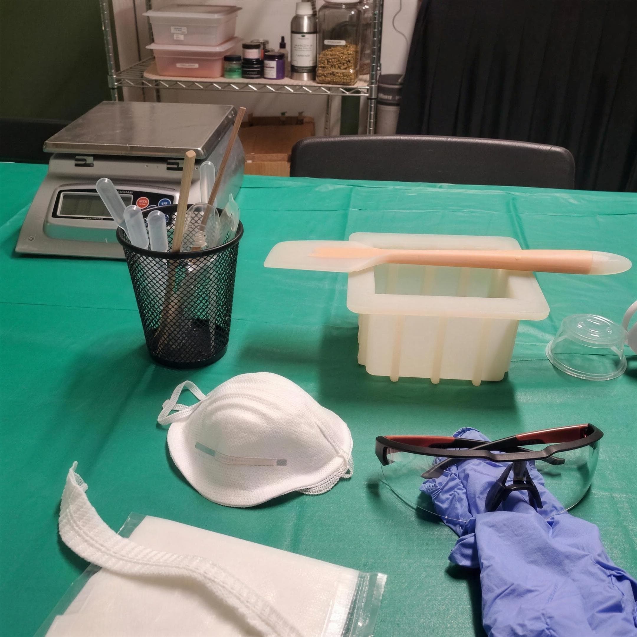 A cold-process soap-making station, scale, loaf mold, spatula, and safety gear, set up for a class at Angry Dog Farms.